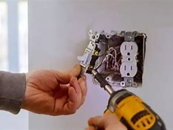 Image of an electrician attaching a wire to an electrical outlet